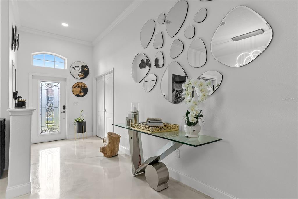 A bright entryway features a glass console table, a wall of decorative mirrors, and tile flooring — 2504 CUMBERLAND CLIFF DRIVE, RUSKIN, FL