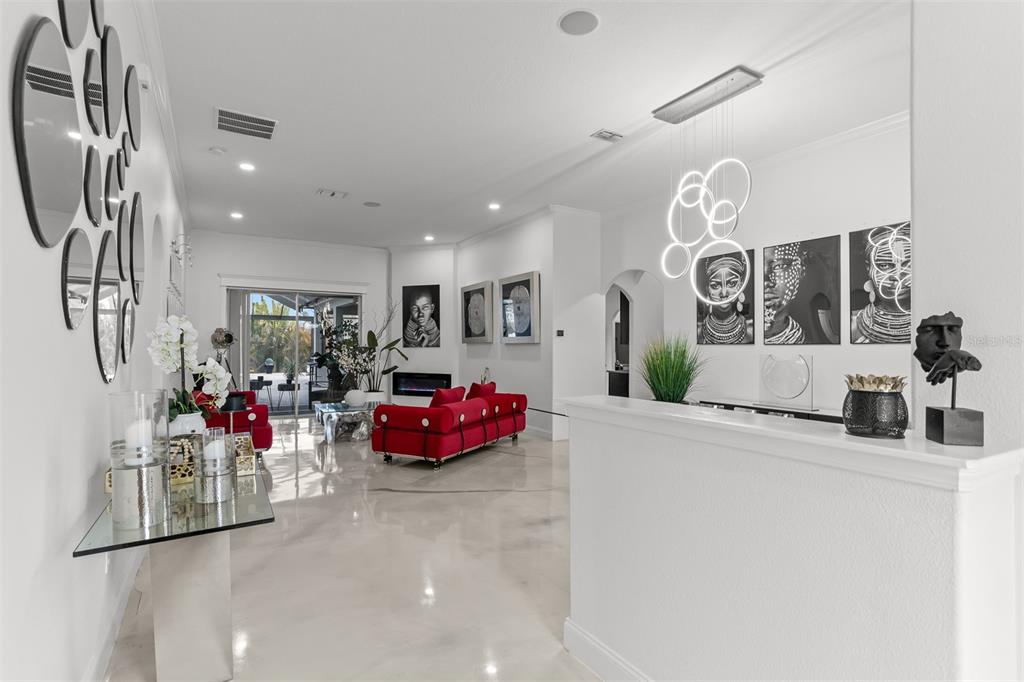 A modern living room features a red sofa, glossy floors, and black and white artwork — 2504 CUMBERLAND CLIFF DRIVE, RUSKIN, FL