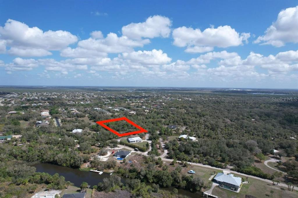 An aerial view shows a rectangular plot of land outlined in red amidst wooded terrain — 1161 HARBOUR EVE COURT, PUNTA GORDA, FL