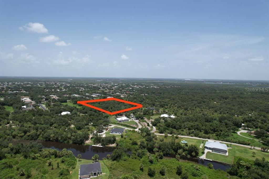 An aerial view shows a rectangular plot of land outlined in red amidst wooded surroundings — 1161 HARBOUR EVE COURT, PUNTA GORDA, FL