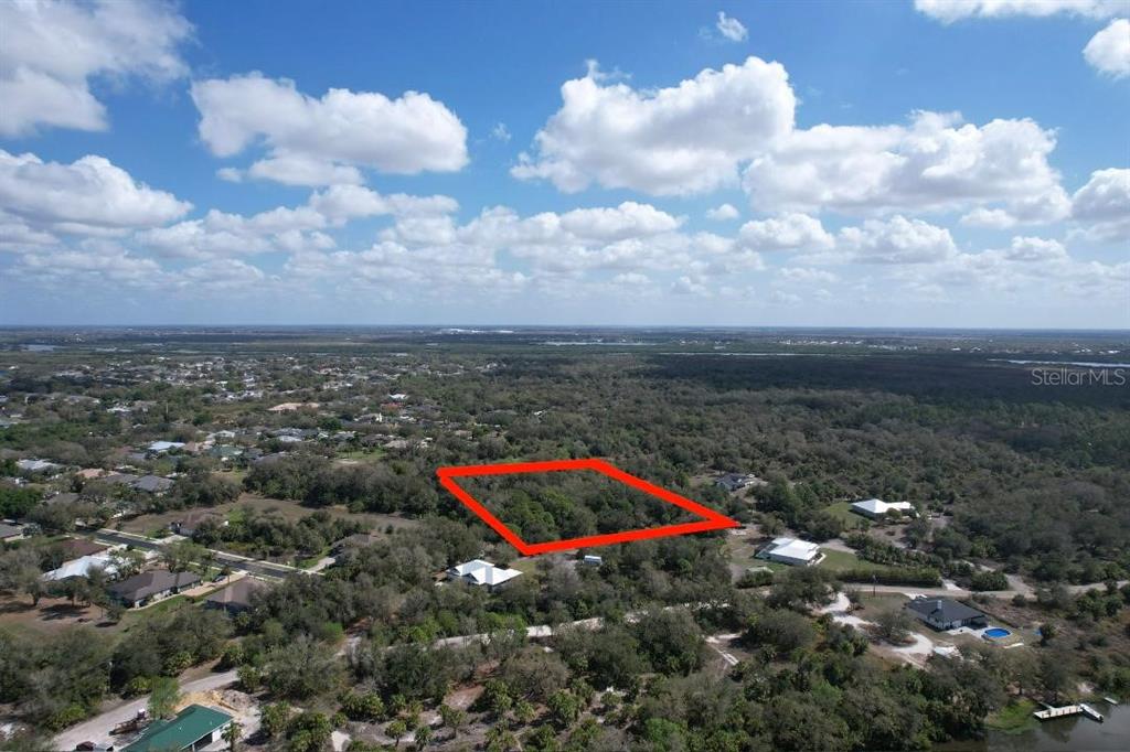 An aerial view shows a rectangular plot of land outlined in red amidst wooded surroundings — 1161 HARBOUR EVE COURT, PUNTA GORDA, FL