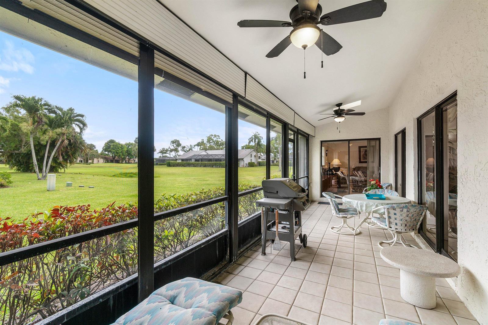 A screened-in patio with tile flooring, a grill, patio furniture, and a view of a golf course — 5692 Willow Creek Lane, Delray Beach FL 33484, DELRAY BEACH, FL
