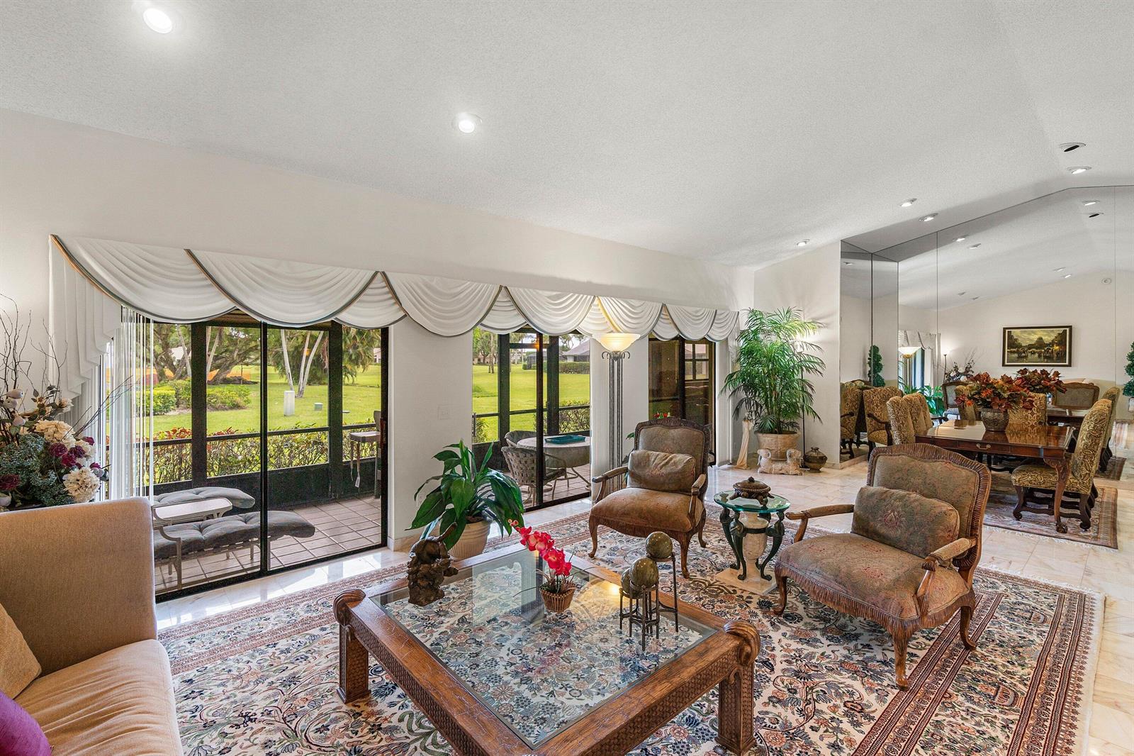 A living room with a patterned rug, glass coffee table, and sliding doors to a patio — 5692 Willow Creek Lane, Delray Beach FL 33484, DELRAY BEACH, FL