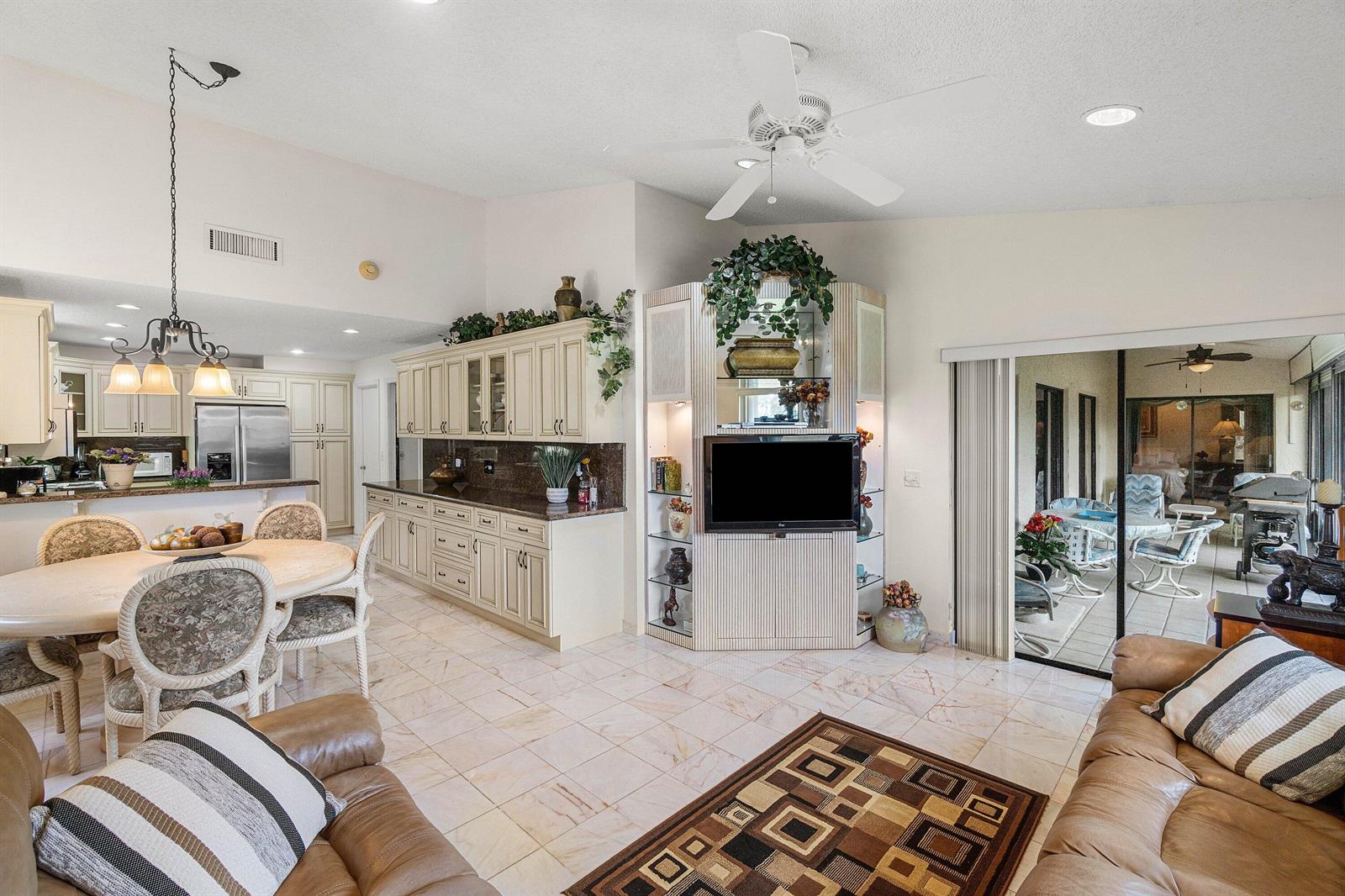 A living and dining area with tile floors, cream cabinetry, and a built-in media center — 5692 Willow Creek Lane, Delray Beach FL 33484, DELRAY BEACH, FL