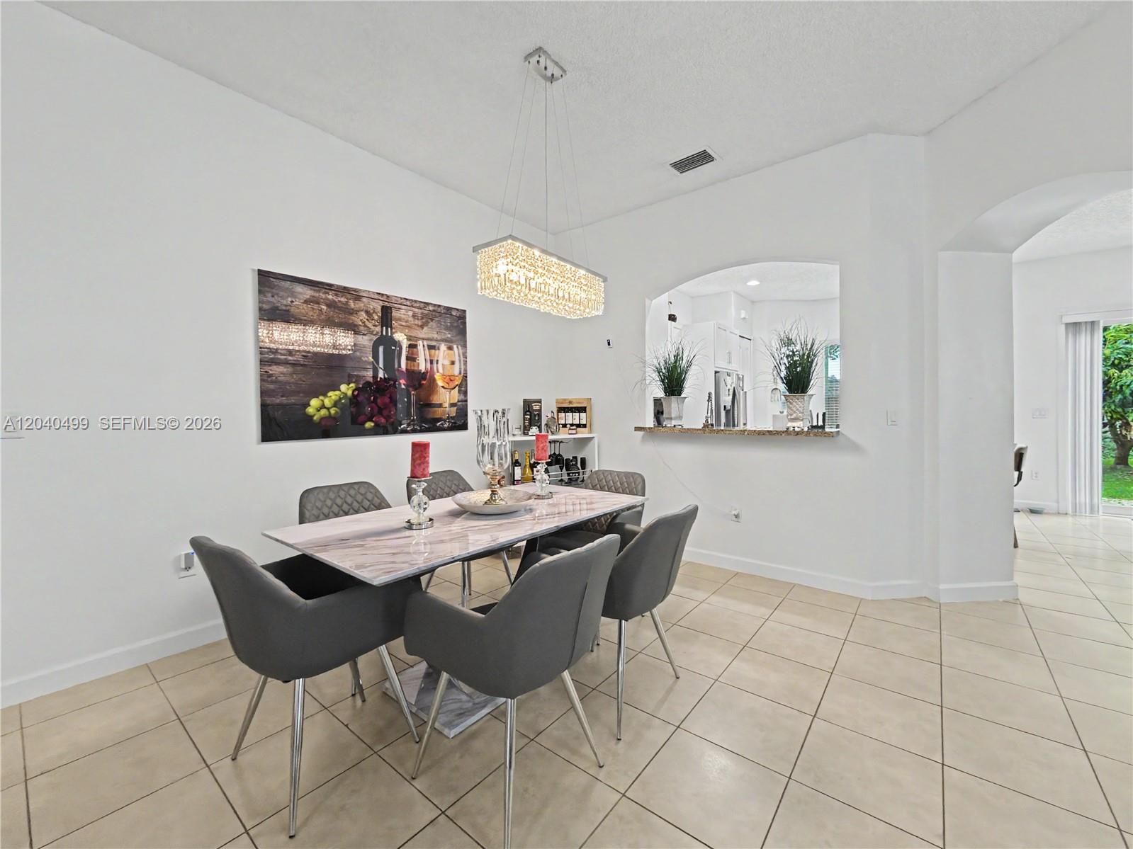 A dining room features a marble-topped table, gray upholstered chairs, and a crystal chandelier — 522 NE 20th Ave, Homestead FL 33033, HOMESTEAD, FL