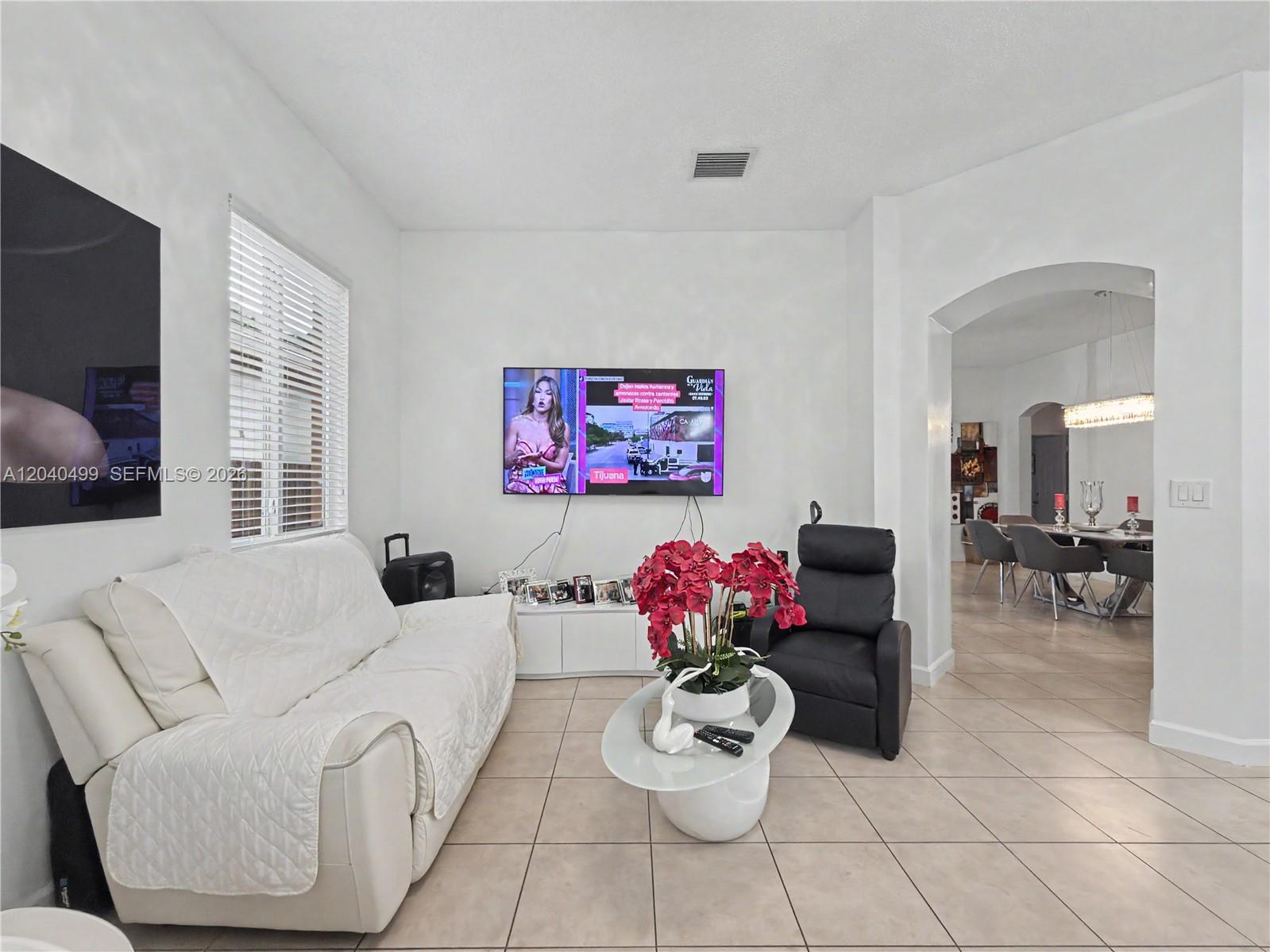 A living room features a white sofa, a black recliner, a television, and tile flooring — 522 NE 20th Ave, Homestead FL 33033, HOMESTEAD, FL