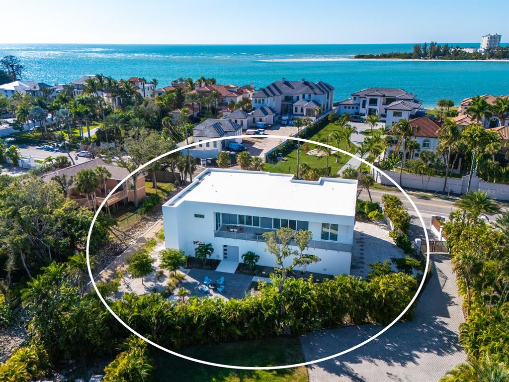 An aerial view shows a modern white two-story house surrounded by lush tropical landscaping — 3939 HIGEL AVENUE, SARASOTA, FL