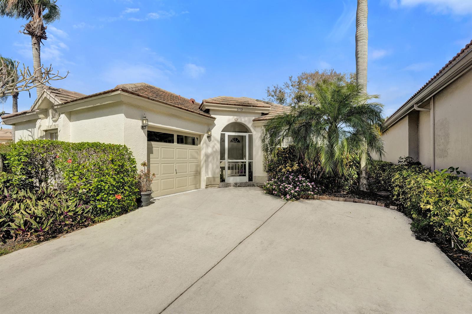 A single-story house with a beige stucco exterior, a garage, and a landscaped front yard — 6115 Bay Isles Drive, Boynton Beach FL 33437, BOYNTON BEACH, FL