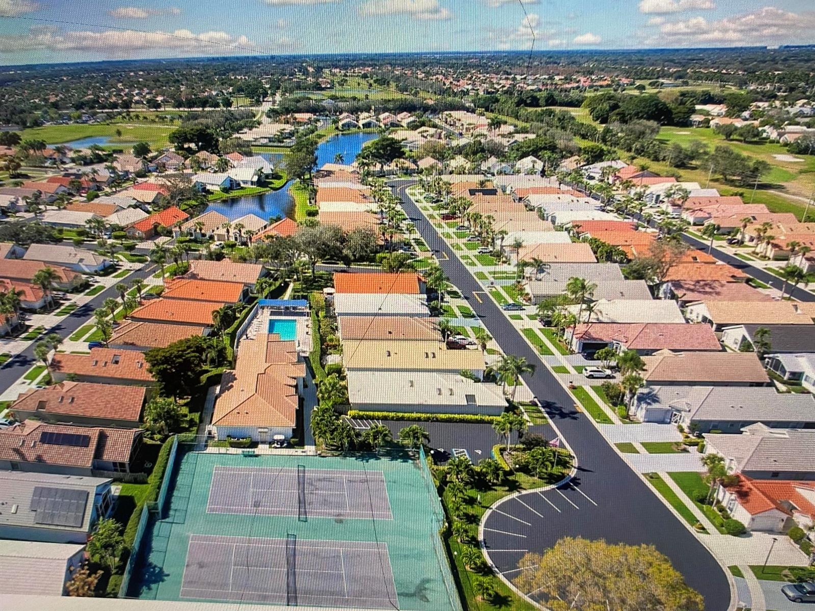 An aerial view of a residential neighborhood featuring a tennis court, pool, and paved streets — 6115 Bay Isles Drive, Boynton Beach FL 33437, BOYNTON BEACH, FL