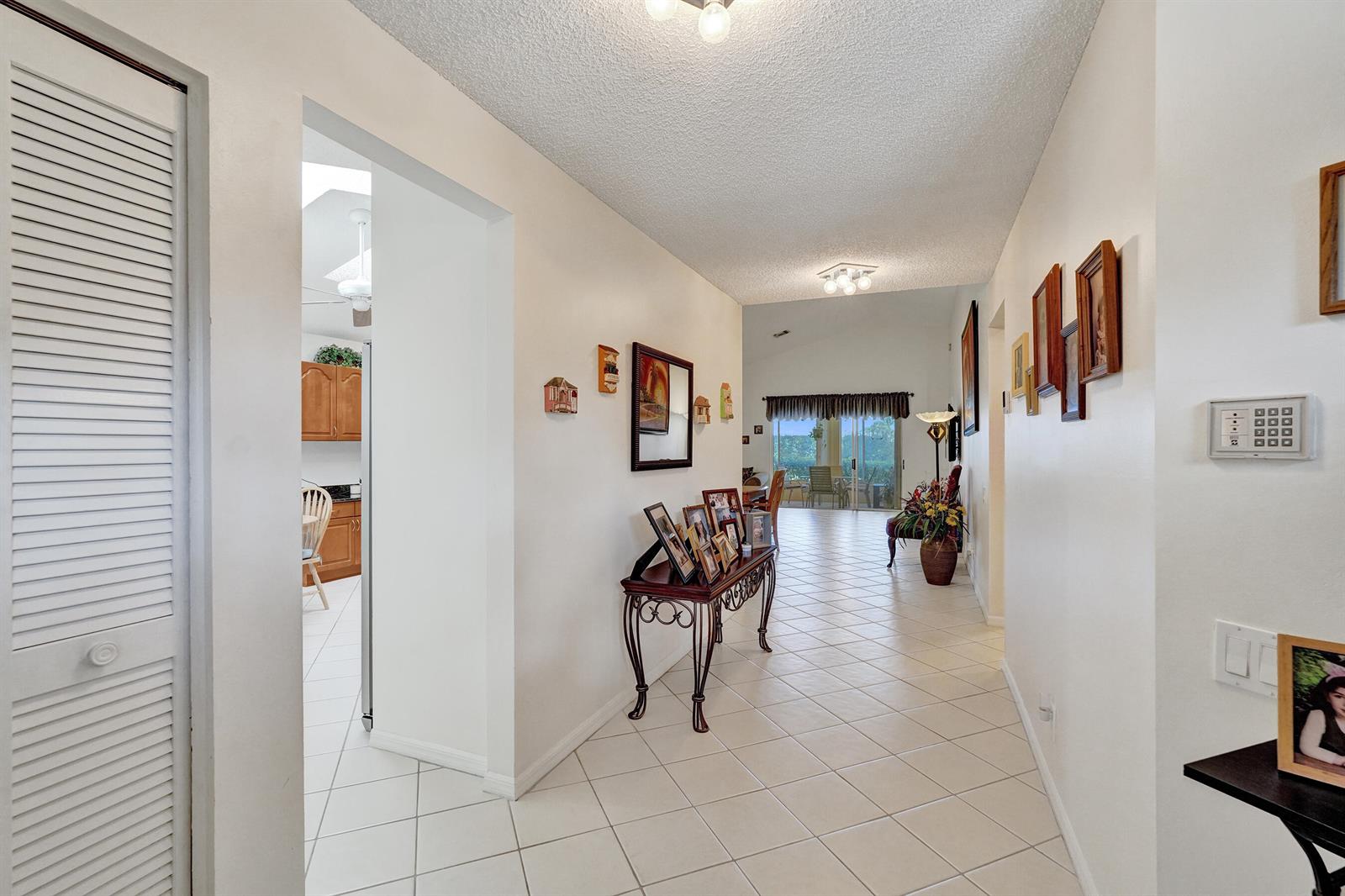 A tiled hallway leads from the entryway toward a living area with sliding glass doors — 6115 Bay Isles Drive, Boynton Beach FL 33437, BOYNTON BEACH, FL