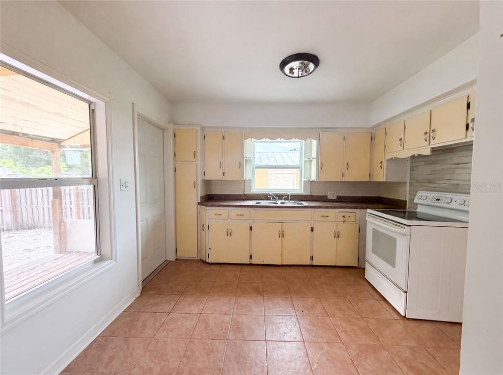 A kitchen with yellow cabinets, a white stove, and brown tile flooring — 2231 9TH AVENUE W, BRADENTON, FL