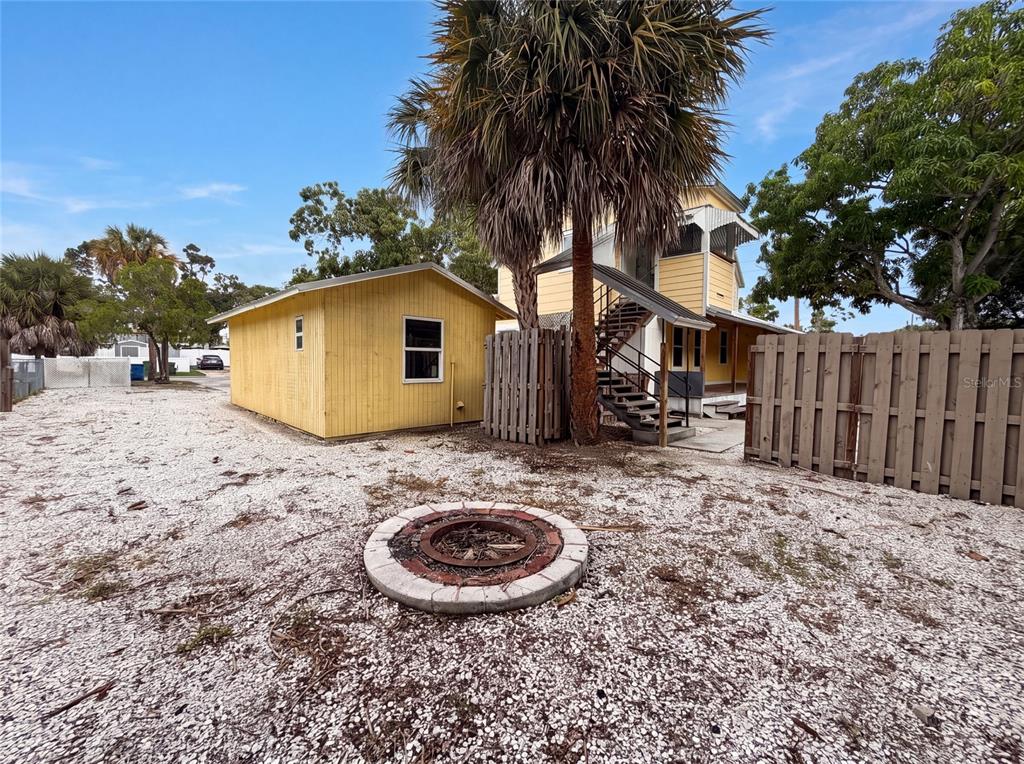 A yellow shed and a two-story house with an outdoor staircase sit on a gravel lot — 2231 9TH AVENUE W, BRADENTON, FL
