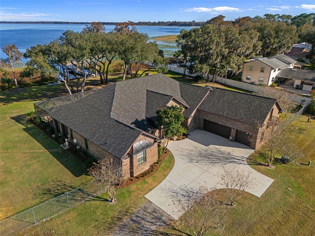 An aerial view of a brick house with a dark shingled roof and lakefront property — 4300 TIMBERLANE ROAD, LAKE WALES, FL