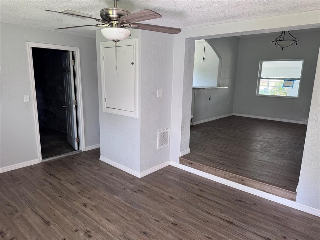 A room with wood-look flooring, a ceiling fan, and a step-up opening to another area — 1142 SW MILDRED STREET, ARCADIA, FL