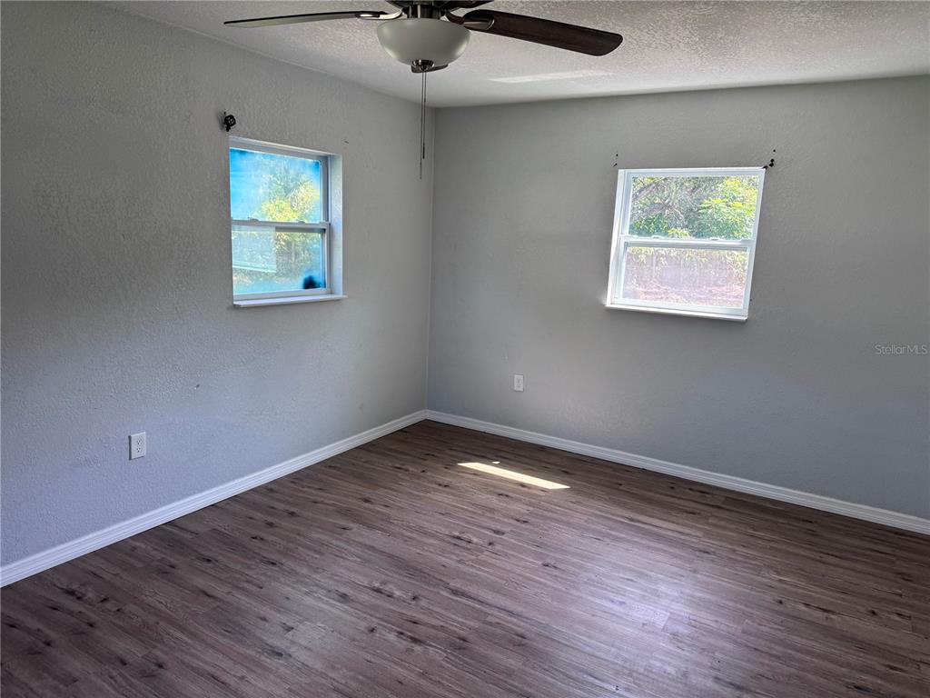 An empty bedroom features gray walls, wood-look flooring, two windows, and a ceiling fan — 1142 SW MILDRED STREET, ARCADIA, FL
