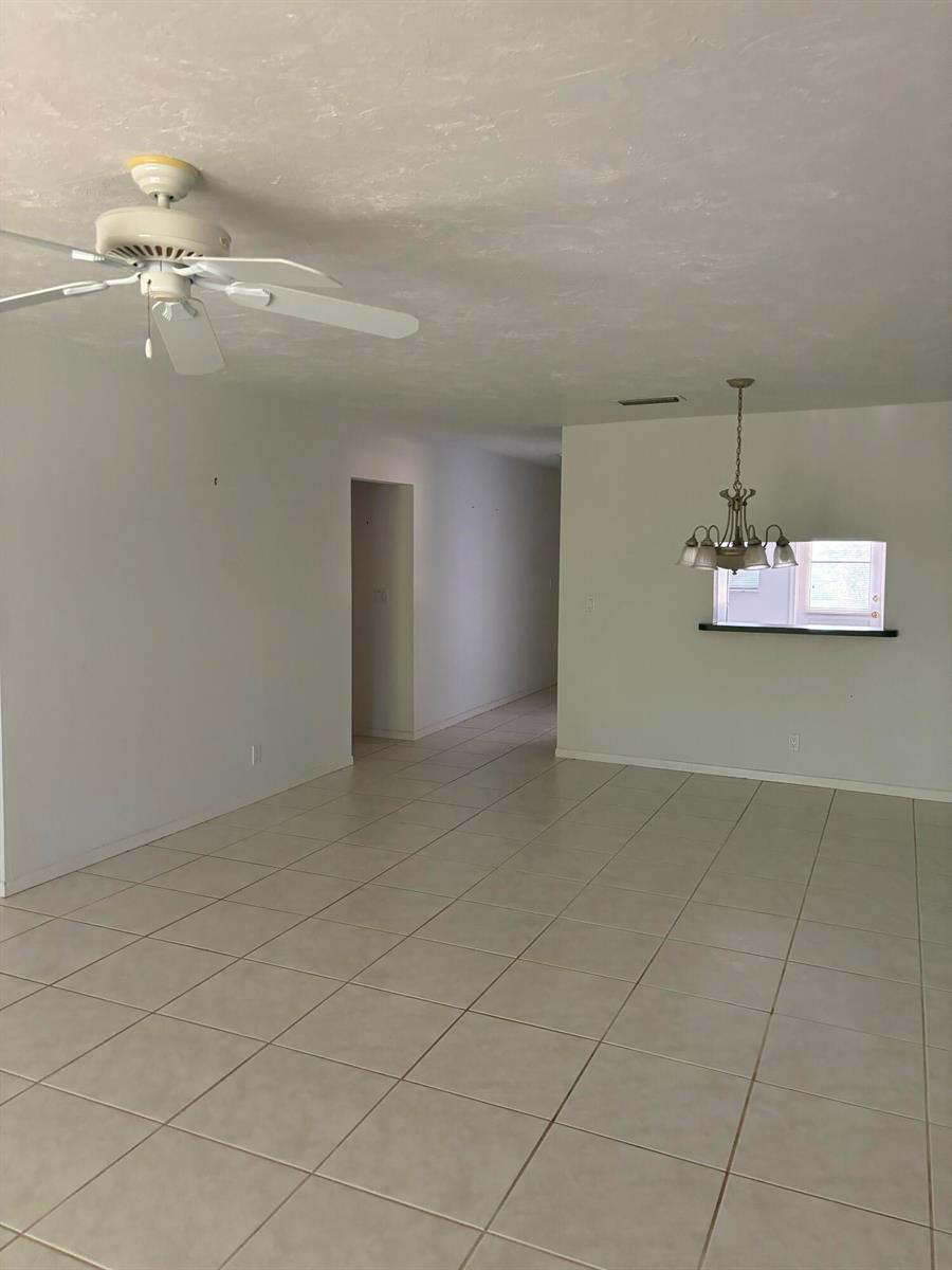 An empty room with light-colored tile flooring, a ceiling fan, and a dining area chandelier — 1700 Dover Road # a, Delray Beach FL 33445, DELRAY BEACH, FL