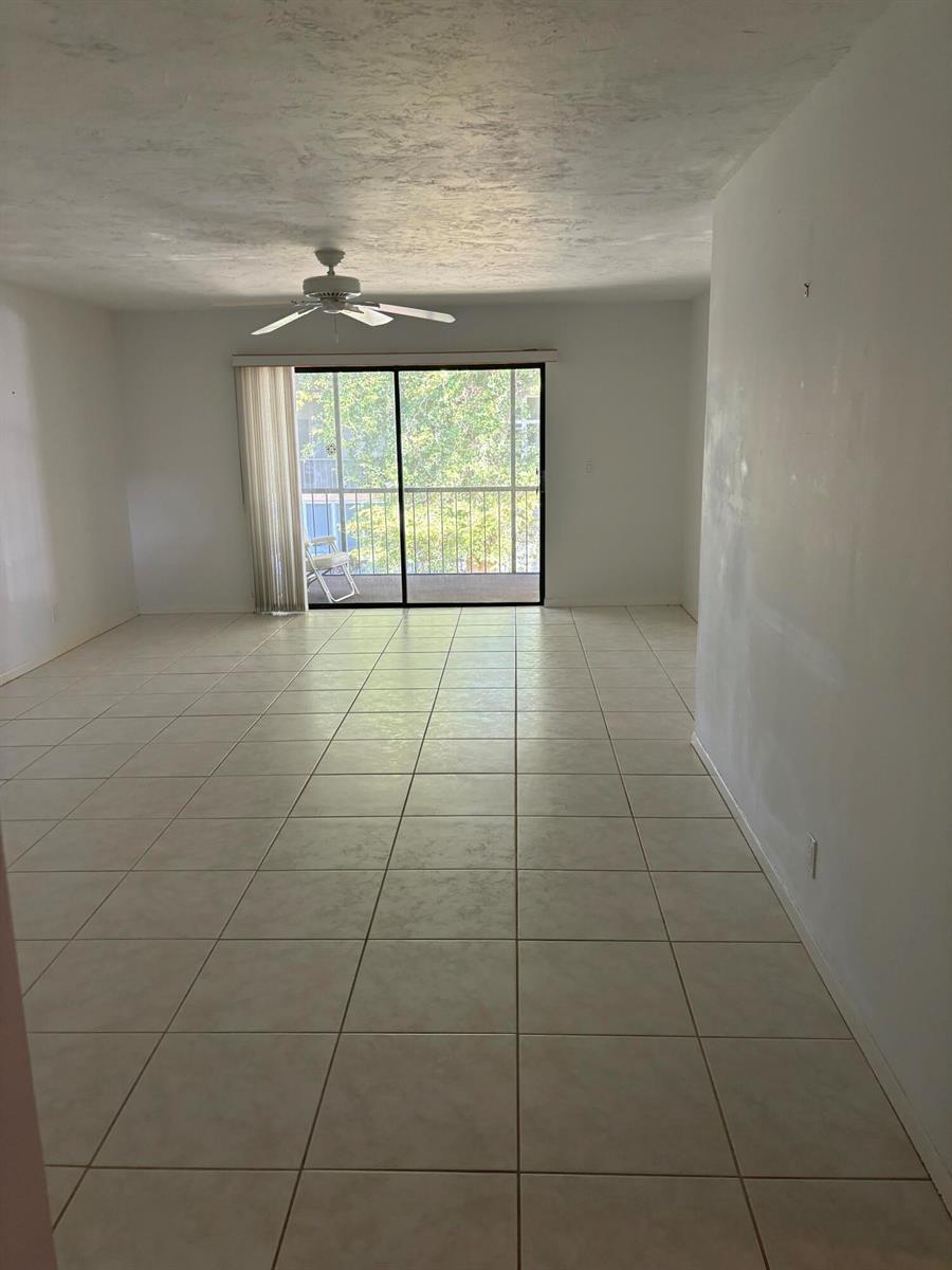 An empty room with light-colored floor tiles, a ceiling fan, and a sliding glass door — 1700 Dover Road # a, Delray Beach FL 33445, DELRAY BEACH, FL