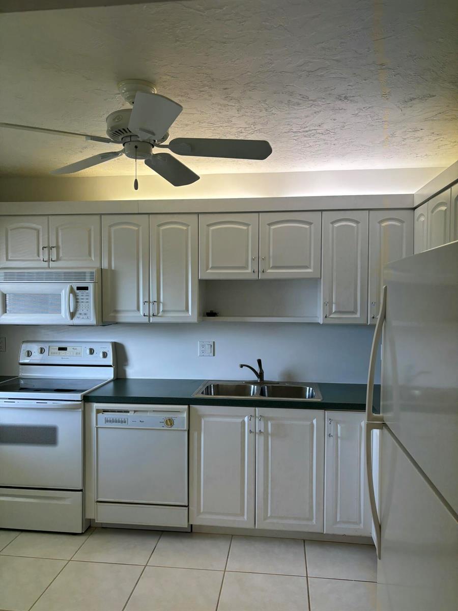 A kitchen features white cabinets, a green countertop, white appliances, and a ceiling fan — 1700 Dover Road # a, Delray Beach FL 33445, DELRAY BEACH, FL