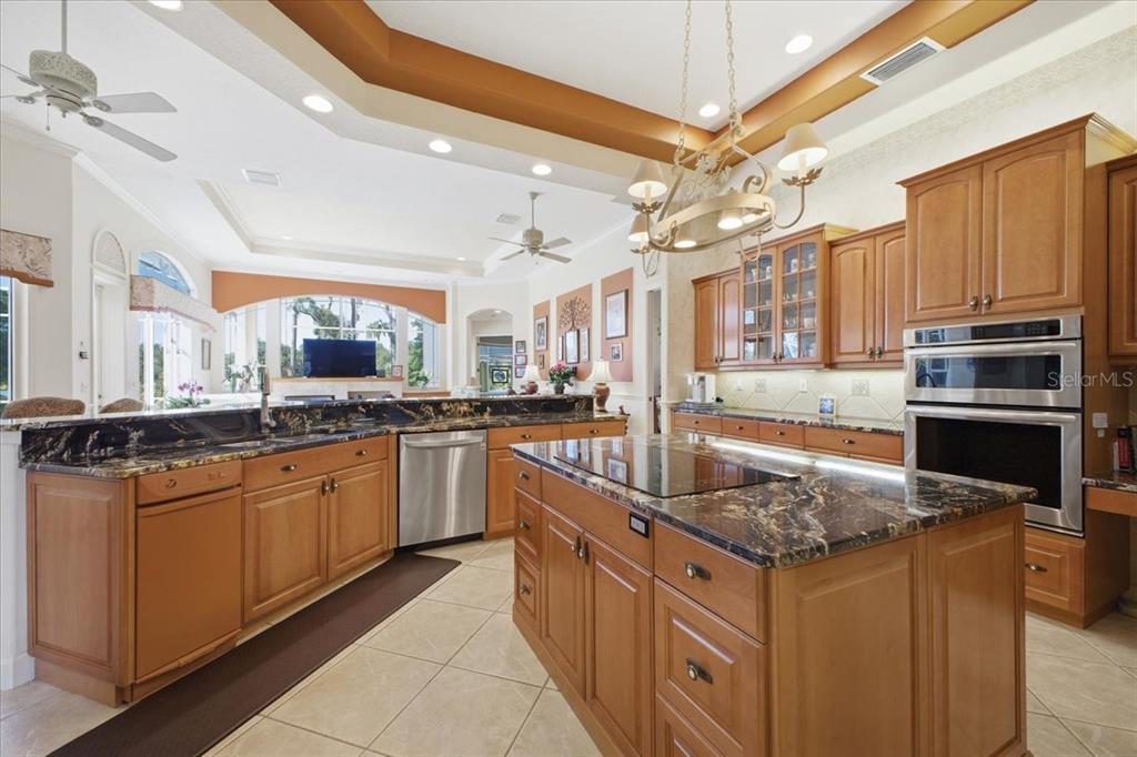 A kitchen features wood cabinets, dark granite countertops, stainless steel appliances, and a central island — 2309 LITTLE COUNTRY ROAD, PARRISH, FL