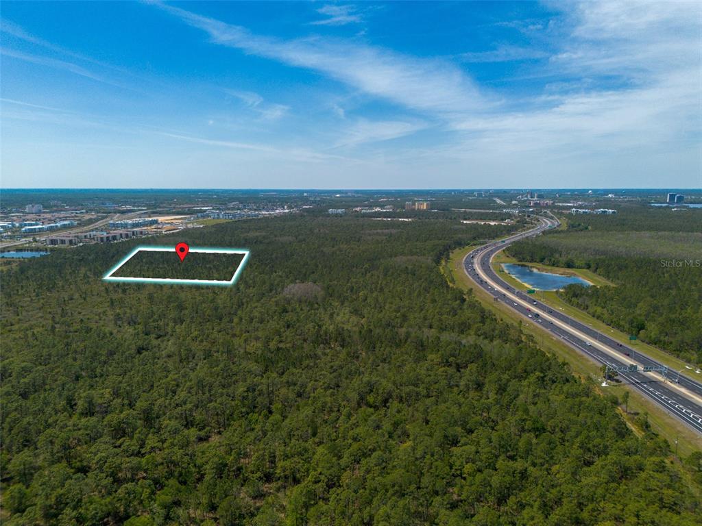 An aerial view shows a rectangular plot of land outlined in white near a highway — SR-535, ORLANDO, FL