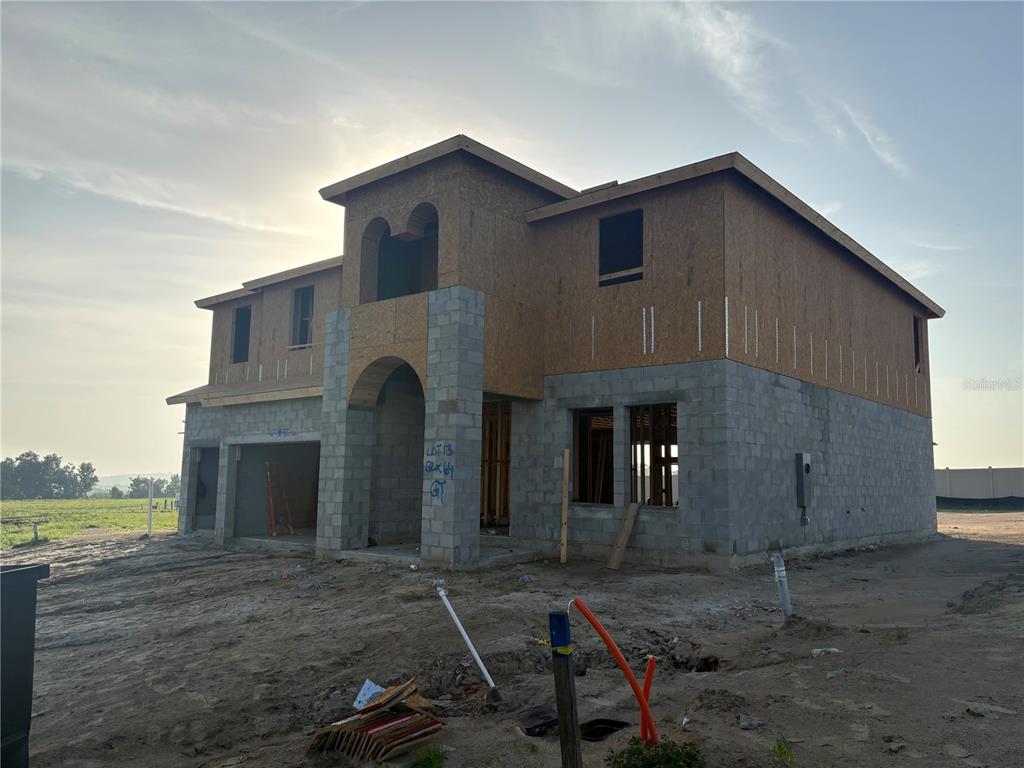 A two-story house under construction with a stucco exterior, arched entryway, and a three-car garage — 9832 LEAF GREEN LANE, DADE CITY, FL