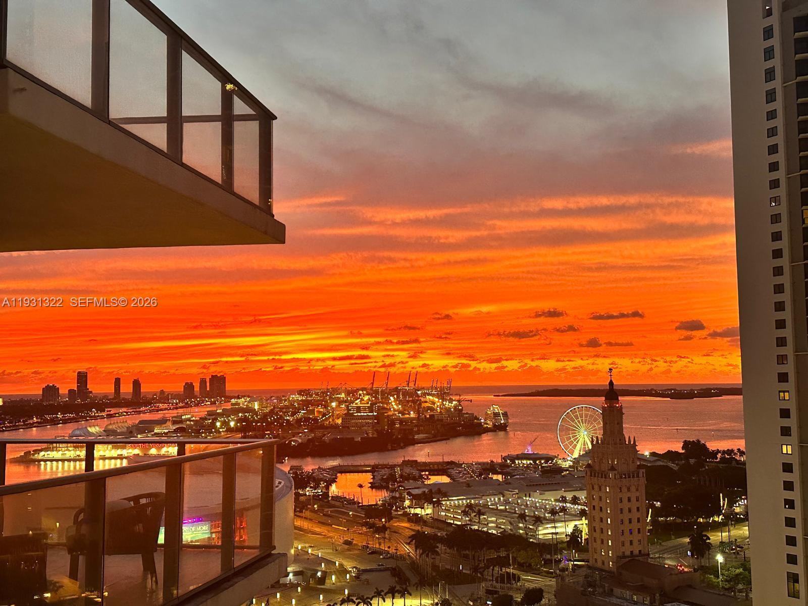 A high-angle view of a sunset over a city skyline, harbor, and ferris wheel — 851 NE 1st Ave # 2212, Miami FL 33132, MIAMI, FL