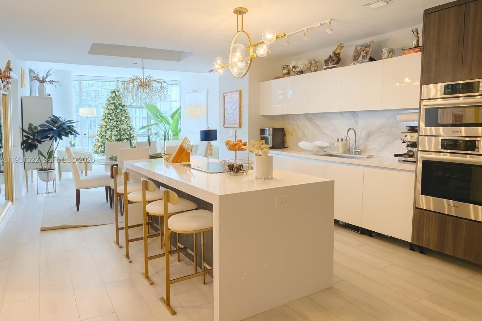 A modern kitchen features a white island with gold stools and sleek cabinetry — 851 NE 1st Ave # 2212, Miami FL 33132, MIAMI, FL