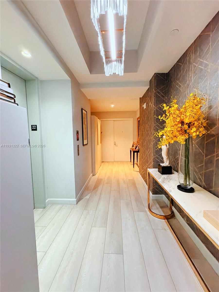 A hallway features light wood flooring, a marble console table, and a geometric patterned wall — 851 NE 1st Ave # 2212, Miami FL 33132, MIAMI, FL