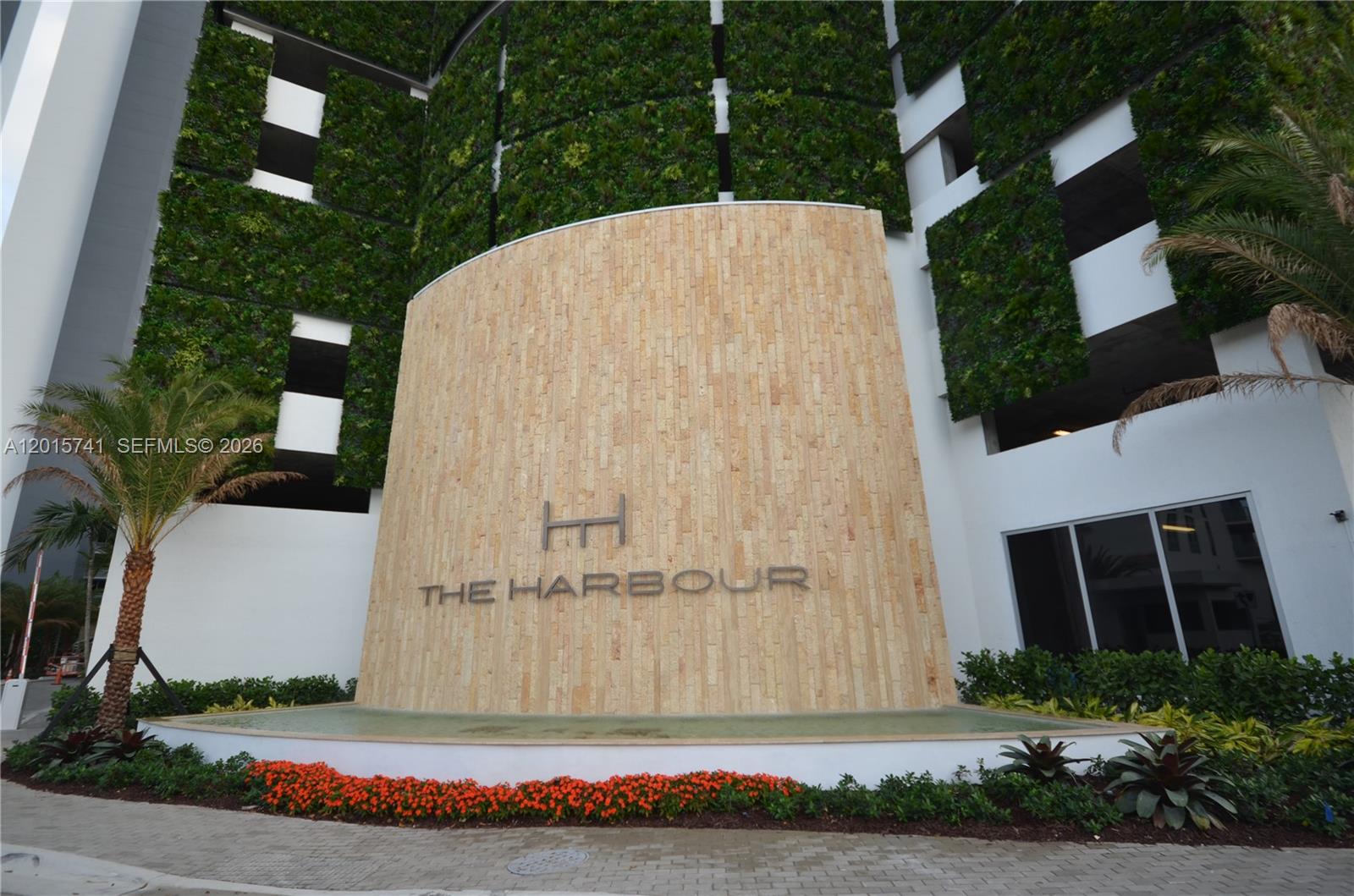 The exterior entrance of The Harbour features a stone wall, vertical gardens, and landscaping — 16385 Biscayne Blvd # 519, North Miami Beach FL 33160, NORTH MIAMI BEACH, FL
