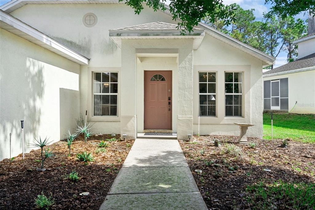 The exterior of a single-story house features a tan front door and a concrete walkway — 301 TROON CIRCLE, DAVENPORT, FL