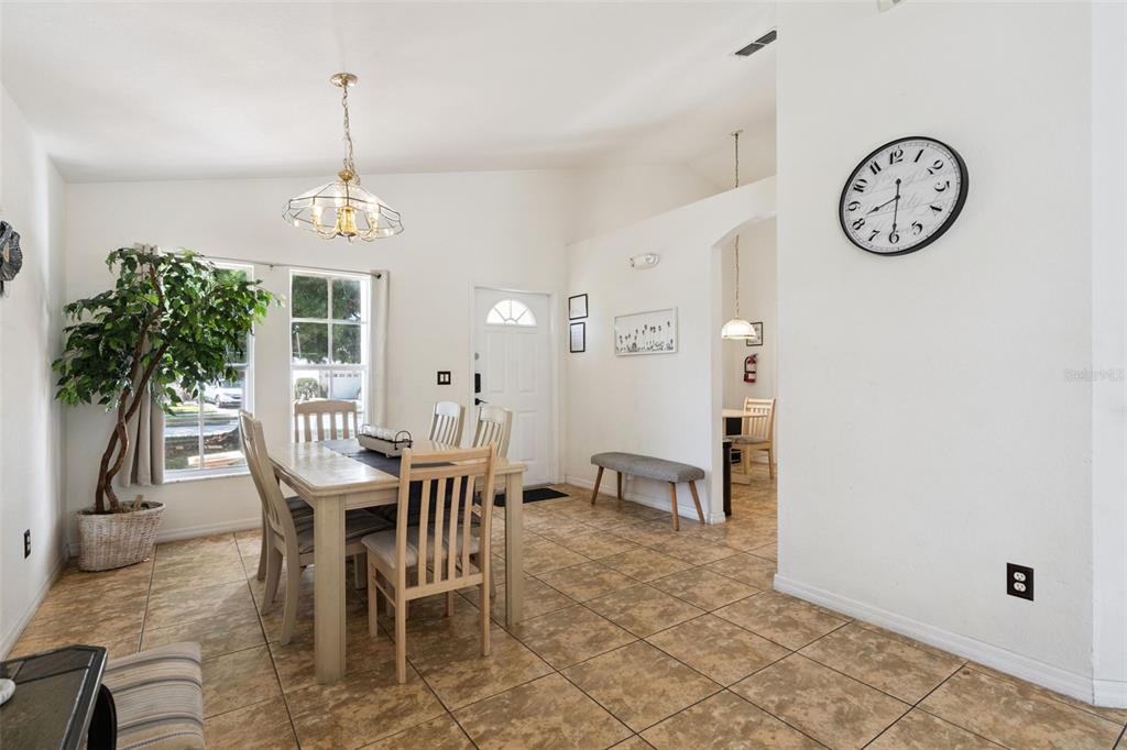 A dining room features tile flooring, a wooden table with chairs, and a wall clock — 301 TROON CIRCLE, DAVENPORT, FL