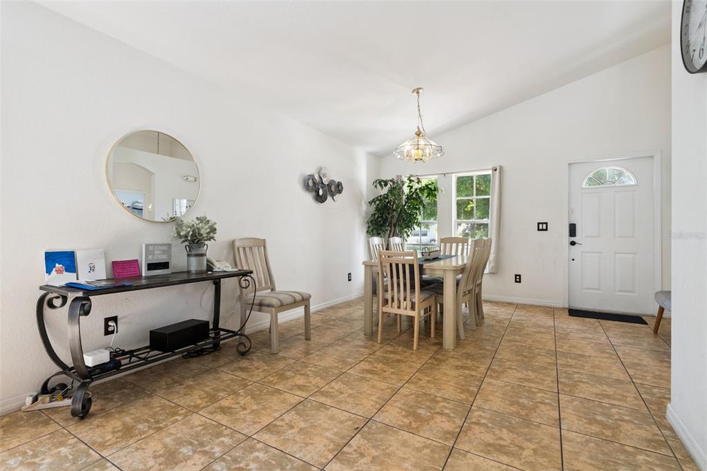 A dining area with tile floors, a wooden table, and a console table with a mirror — 301 TROON CIRCLE, DAVENPORT, FL