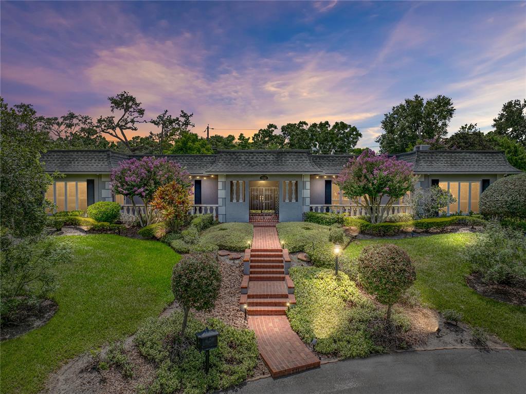 A single-story house with a brick walkway, manicured landscaping, and a dark shingled roof — 1249 LAKE POINT DRIVE, LAKELAND, FL