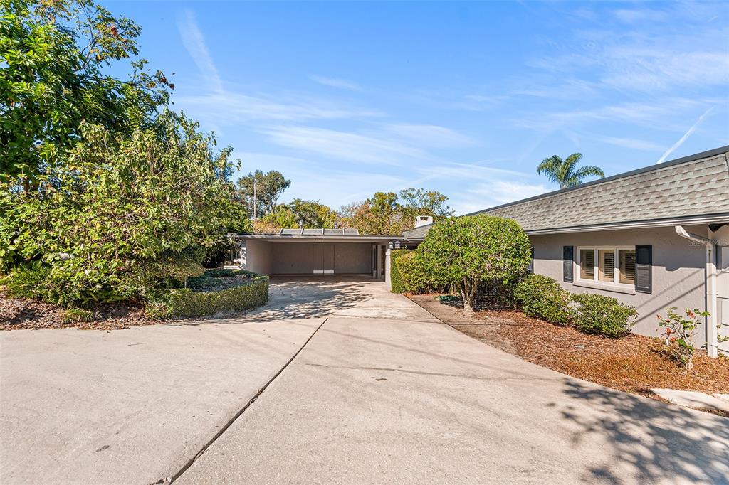 A concrete driveway leads to a covered carport beside a single-story house with gray siding — 1249 LAKE POINT DRIVE, LAKELAND, FL