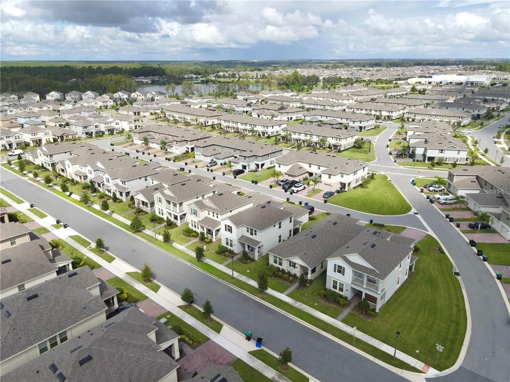 An aerial view shows a suburban neighborhood with multi-family residential buildings, paved streets, and landscaping — 16031 SCARPETTA STREET, WINTER GARDEN, FL