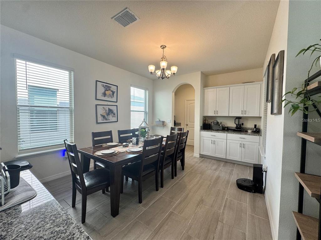 A dining room features a dark wood table, white cabinetry, and light tile flooring — 16031 SCARPETTA STREET, WINTER GARDEN, FL
