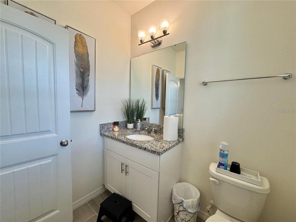 A bathroom features a granite vanity, white cabinetry, a mirror, and a toilet — 16031 SCARPETTA STREET, WINTER GARDEN, FL