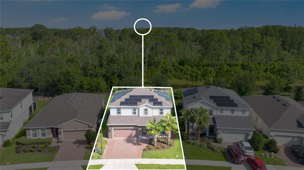 An aerial view of a two-story house with solar panels on the roof and a driveway — 17096 GOLDCREST LOOP, CLERMONT, FL