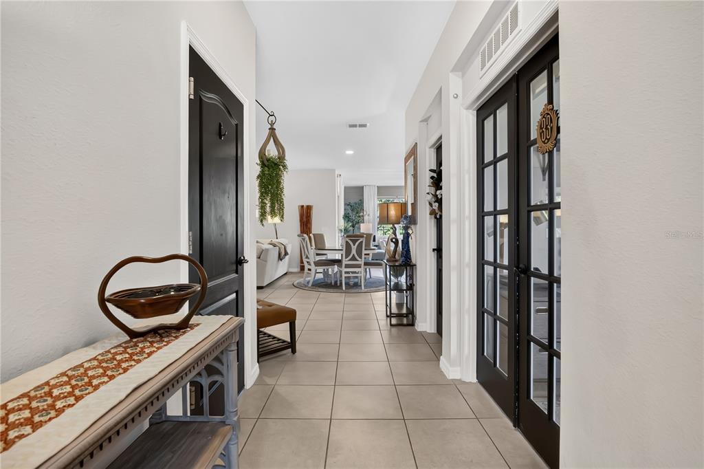 A tiled hallway leads from a foreground entryway toward a dining area and living room — 17096 GOLDCREST LOOP, CLERMONT, FL