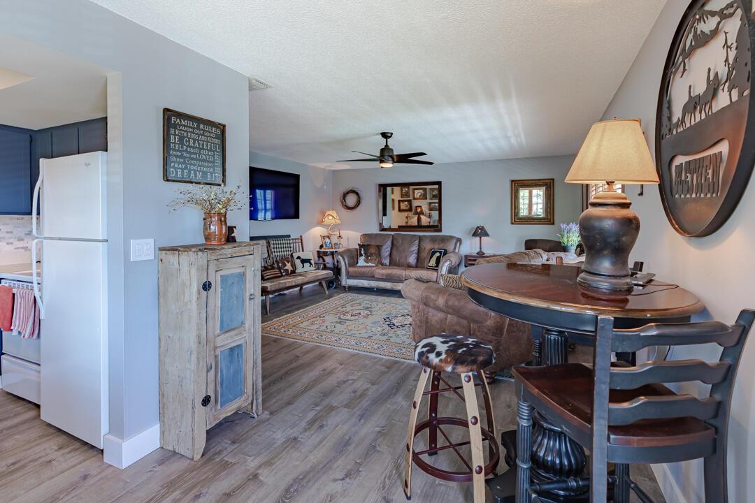 A living room with wood-look flooring, leather furniture, a ceiling fan, and a dining area — 2929 SE Ocean Boulevard # 10, Stuart FL 34996, STUART, FL