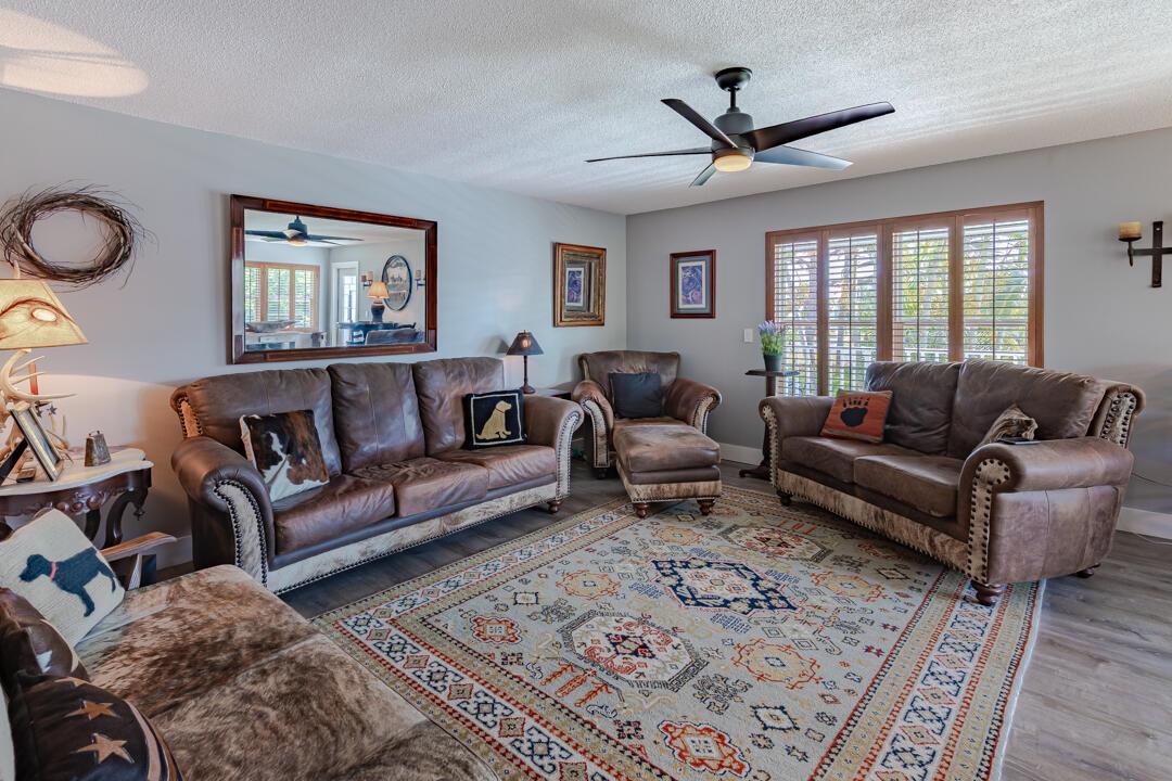 A living room features leather sofas, a patterned area rug, and a ceiling fan — 2929 SE Ocean Boulevard # 10, Stuart FL 34996, STUART, FL