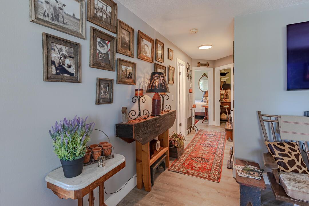 A hallway features a gallery wall, a rustic console table, and a red patterned runner rug — 2929 SE Ocean Boulevard # 10, Stuart FL 34996, STUART, FL