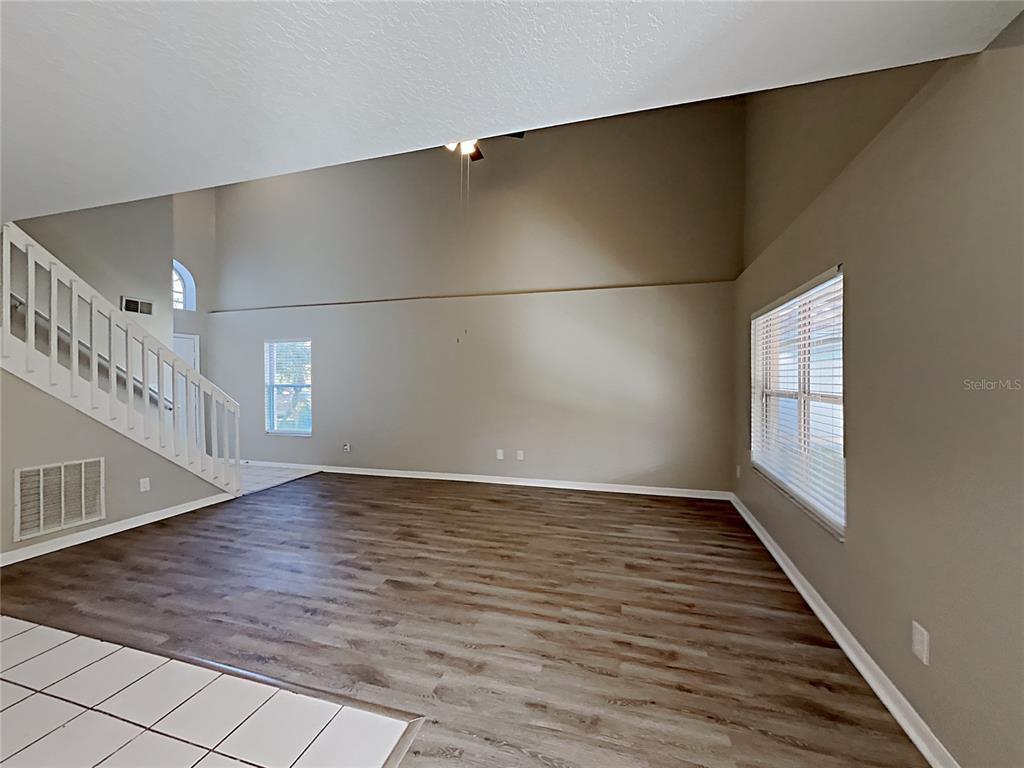 A living room with high ceilings, wood-look flooring, a staircase, and large windows — 2184 HEATHWOOD CIRCLE, ORLANDO, FL