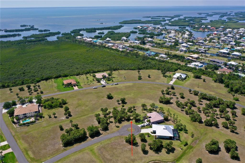 An aerial view shows a residential lot with a red arrow pointing toward it — 16091 CHITLAN COURT, PUNTA GORDA, FL