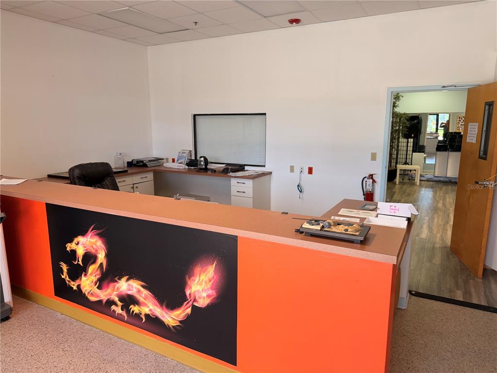 A reception desk with a dragon graphic sits in an office space with white walls — 2 MCCORMICK DRIVE, PALM COAST, FL