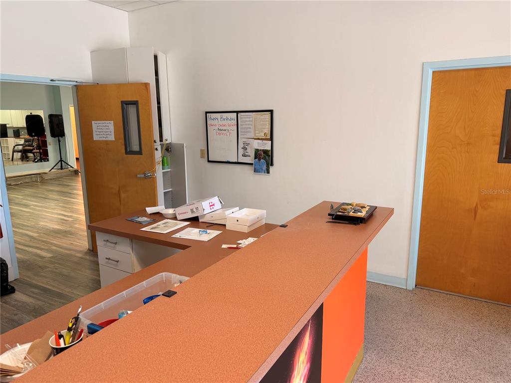 A reception area features a large L-shaped desk, a bulletin board, and two wooden doors — 2 MCCORMICK DRIVE, PALM COAST, FL