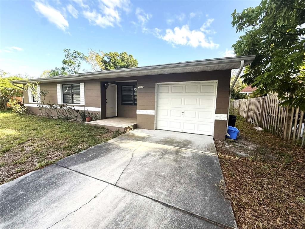 A single-story house with a brown exterior, white garage door, and a concrete driveway — 5740 65TH TERRACE N, PINELLAS PARK, FL