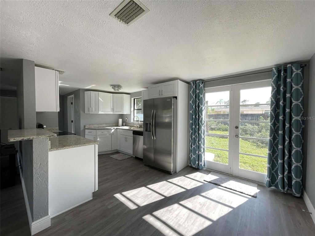 A kitchen with white cabinets, granite countertops, stainless steel appliances, and glass doors to a yard — 5740 65TH TERRACE N, PINELLAS PARK, FL