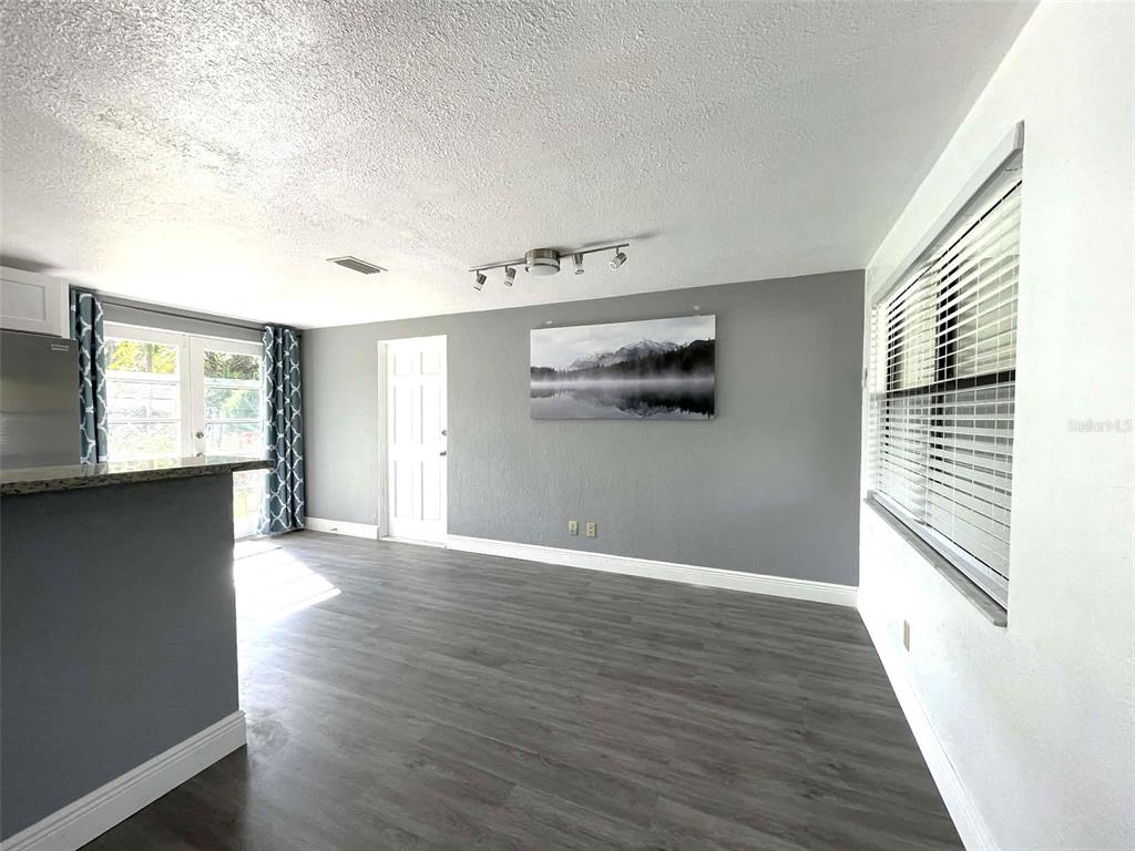 A living area features gray walls, wood-look flooring, a ceiling light fixture, and a window — 5740 65TH TERRACE N, PINELLAS PARK, FL