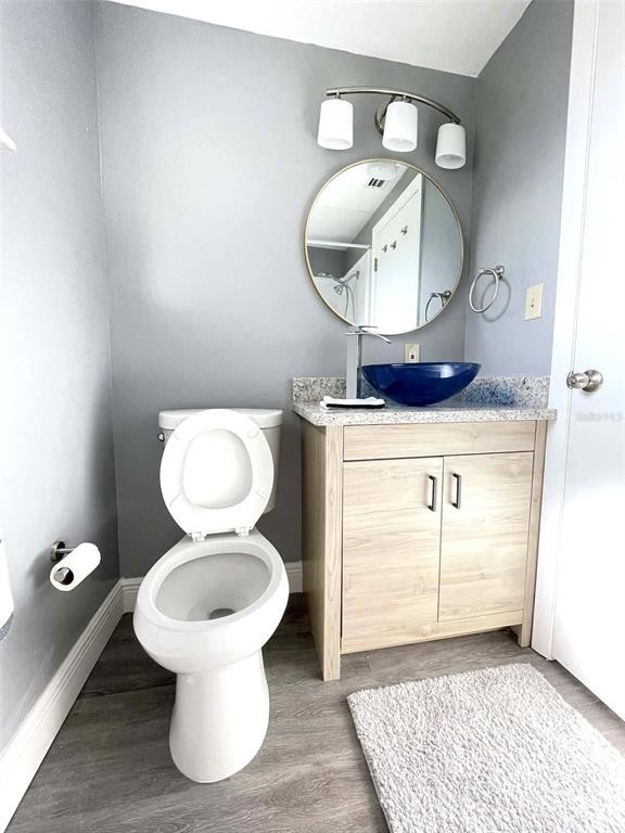 A bathroom features a light wood vanity, a blue vessel sink, and a round mirror — 5740 65TH TERRACE N, PINELLAS PARK, FL